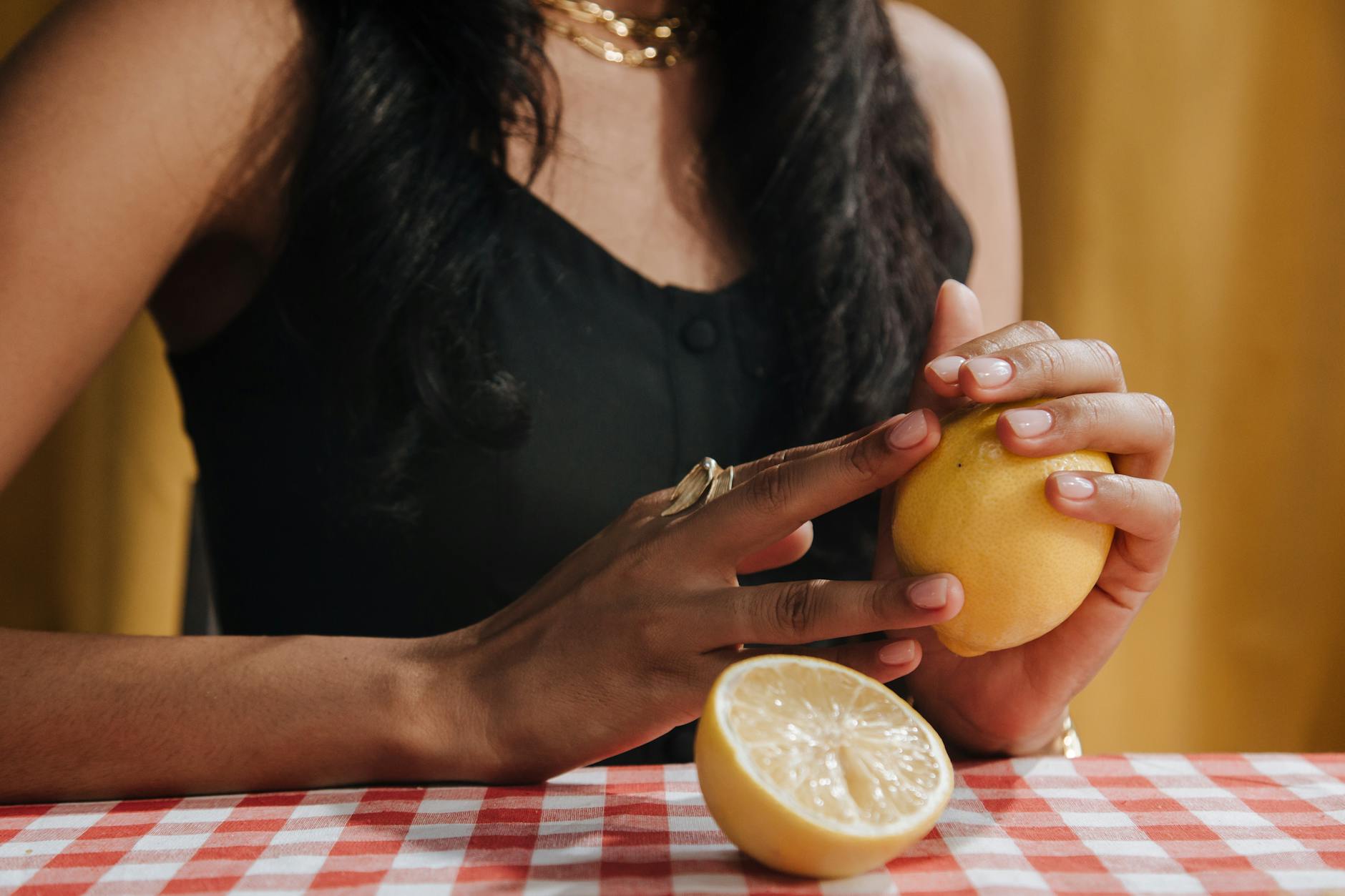A hand holding a lemon vibrator against a minimalistic purple backdrop