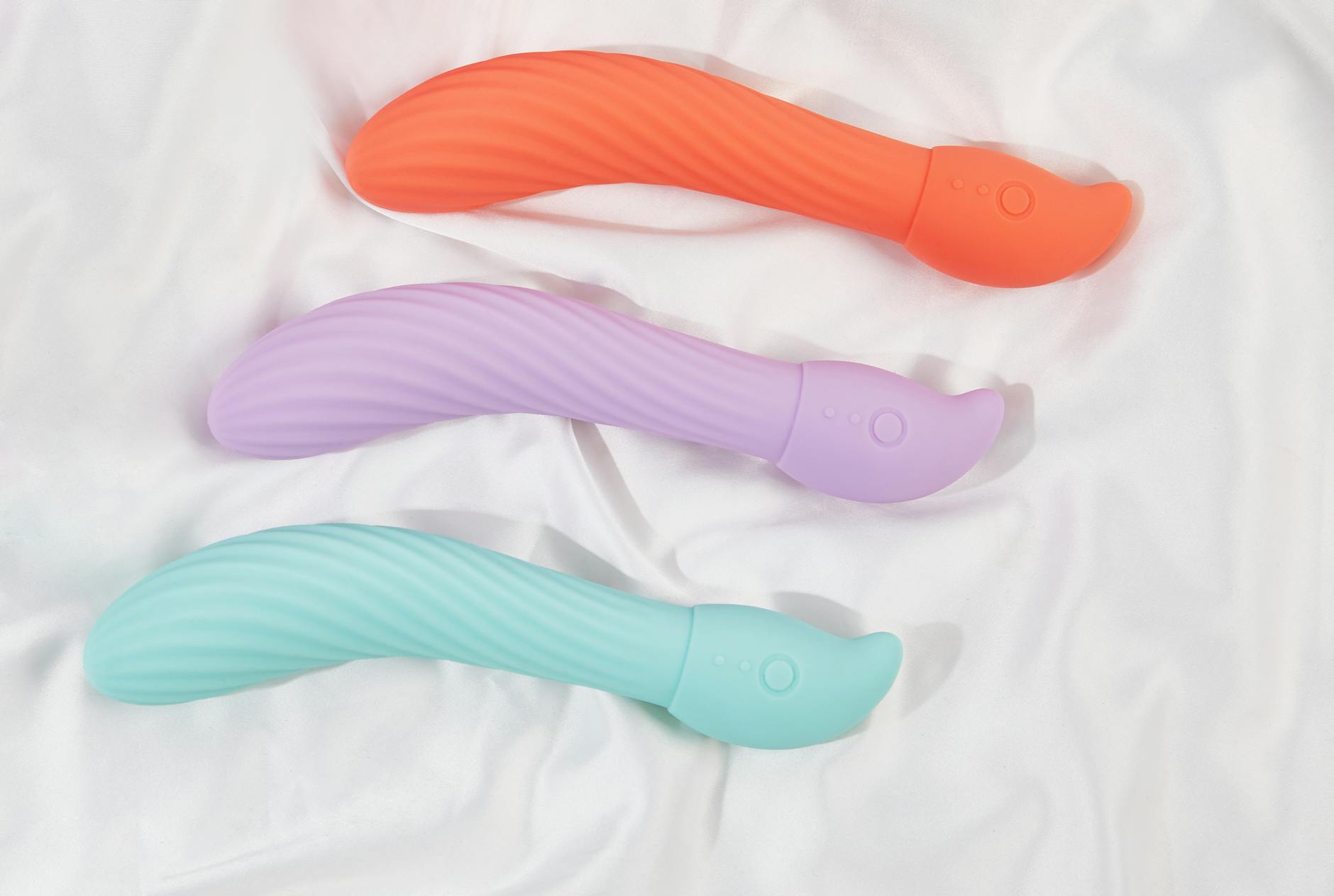 A teal lemon vibrator resting on smooth white silk fabric in studio lighting
