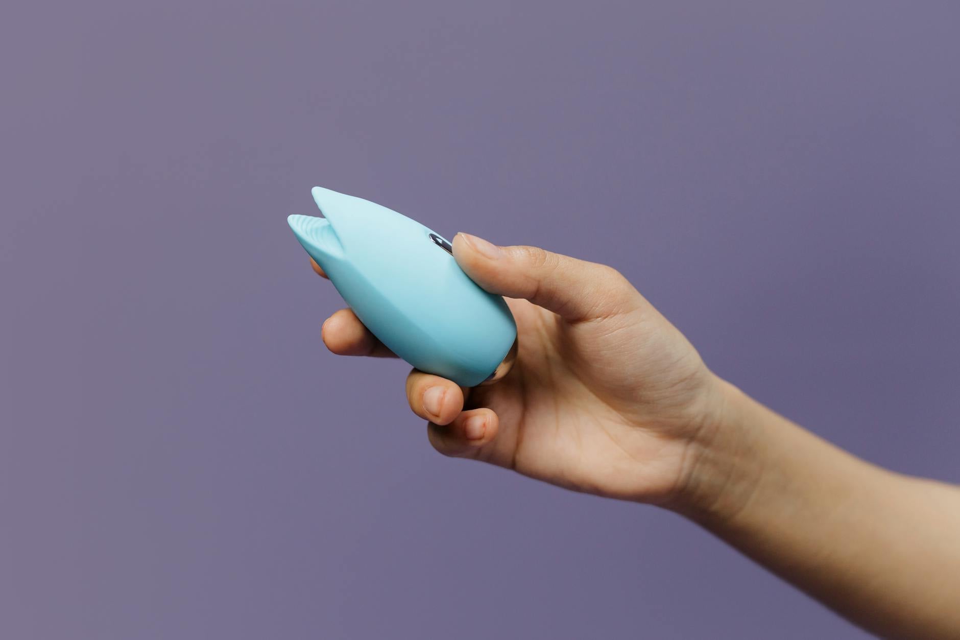Un elegante vibratore teal su tessuto di seta bianco, perfetto per l'intimità consapevole