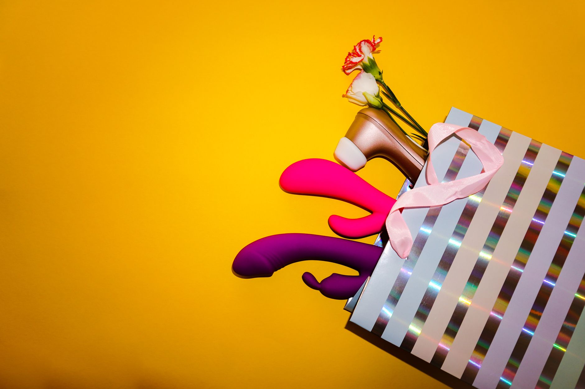 Collezione colorata di vibratori in una busta regalo olografica con sfondo giallo brillante