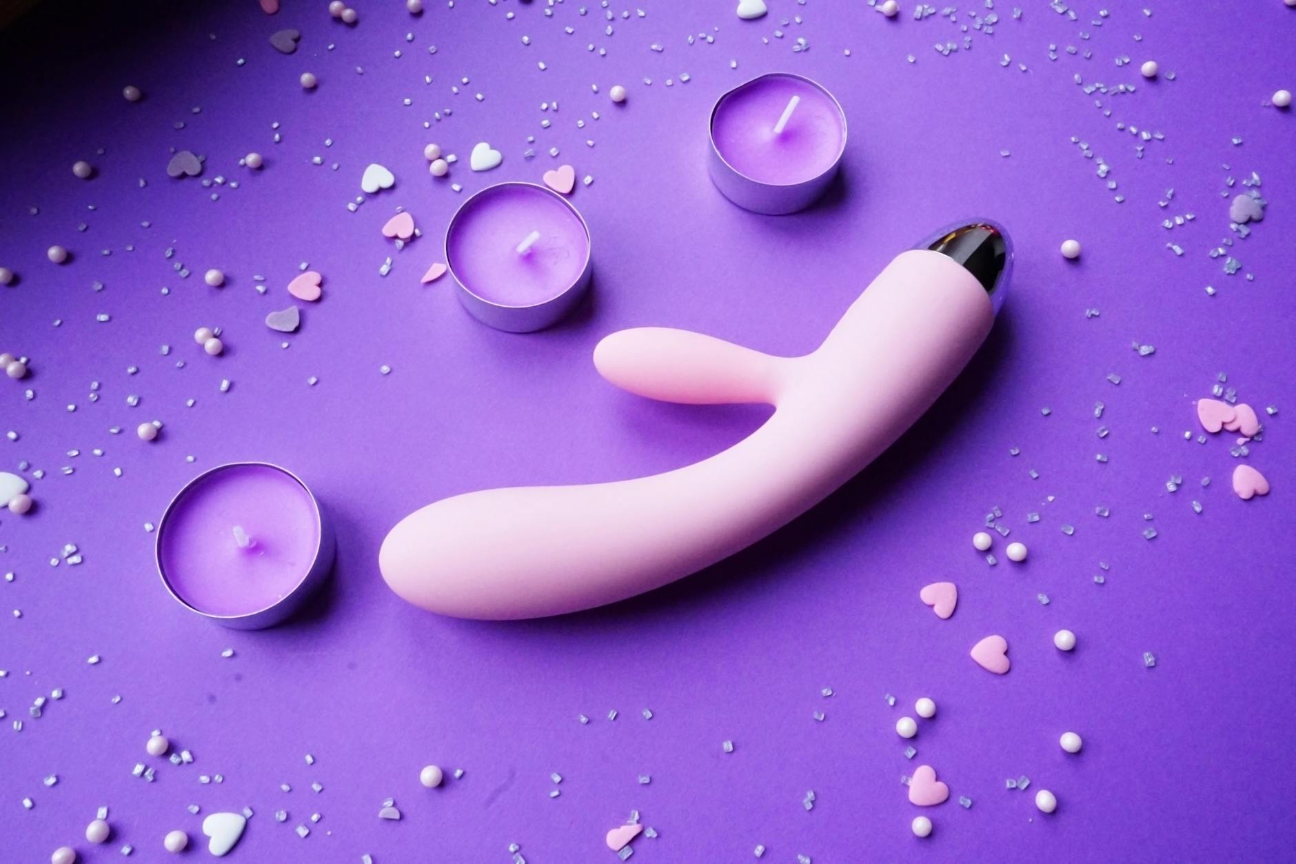 Pink vibrator on purple background with romantic mood lighting and candles